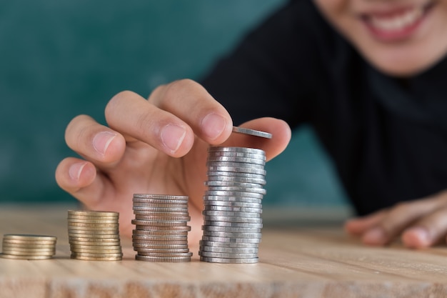 Jeune femme heureuse insérer la pièce sur l&#39;empilé de pièces de monnaie sur le bureau