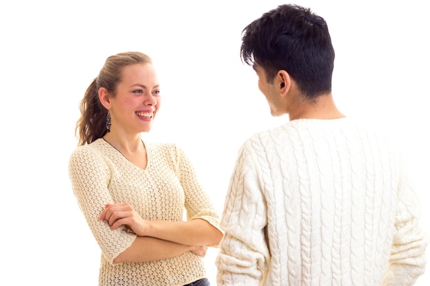 Jeune femme heureuse avec une longue queue de cheval châtaigne et jeune bel homme en chandails blancs parlant