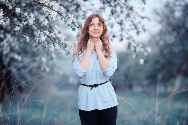 jeune femme heureuse marchant dans un verger de pommes au printemps fleurs blanches