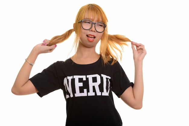 Jeune femme heureuse de nerd asiatique souriant et jouant avec ses cheveux