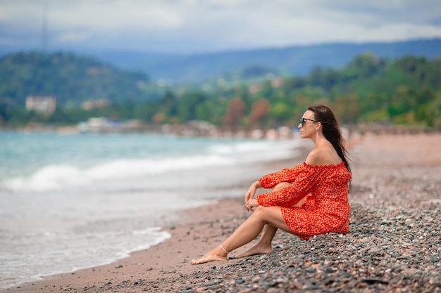 Jeune femme heureuse sur la plage avec vue sur la montagne