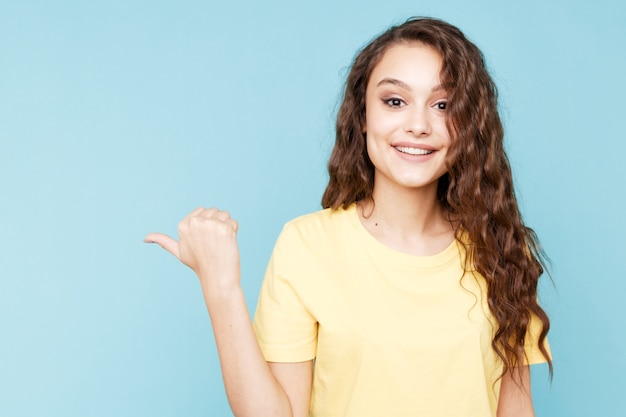 Jeune femme heureuse pointant vers la gauche par son doigt.