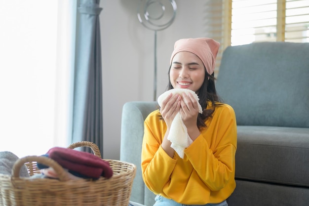 Jeune femme heureuse portant des vêtements pliants en chemise jaune dans le concept de blanchisserie du salon