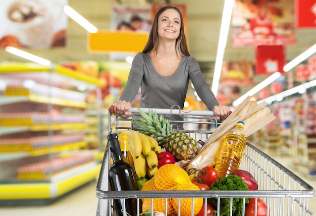 Jeune femme heureuse poussant le caddie dans le magasin