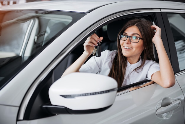 Jeune femme heureuse près de la voiture avec les clés en main