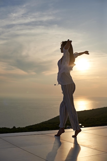 une jeune femme heureuse profite du coucher du soleil en dansant et écoute de la musique au casque