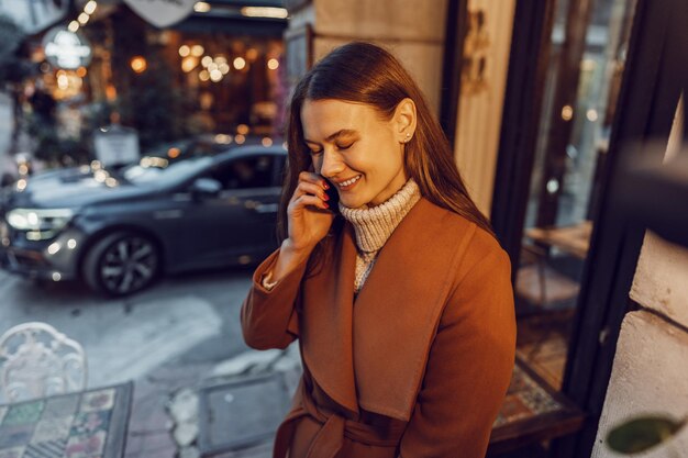 Photo une jeune femme heureuse qui parle au téléphone dans la rue.