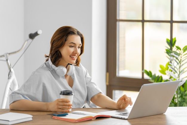 Une jeune femme heureuse qui travaille et regarde un podcast de webinaire sur son ordinateur portable ayant une conversation à distance