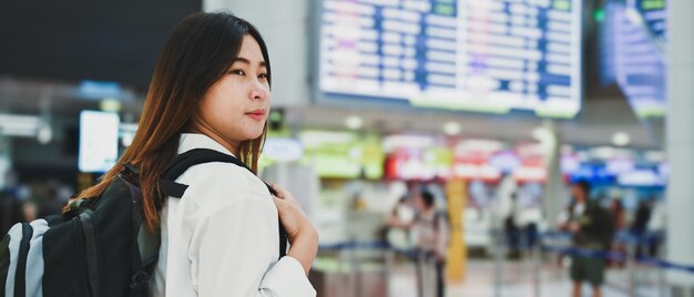 Une jeune femme heureuse avec un sac à dos attend l'embarquement à l'aéroport