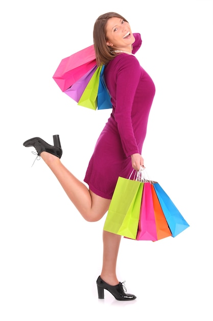 une jeune femme heureuse avec des sacs à provisions sur blanc