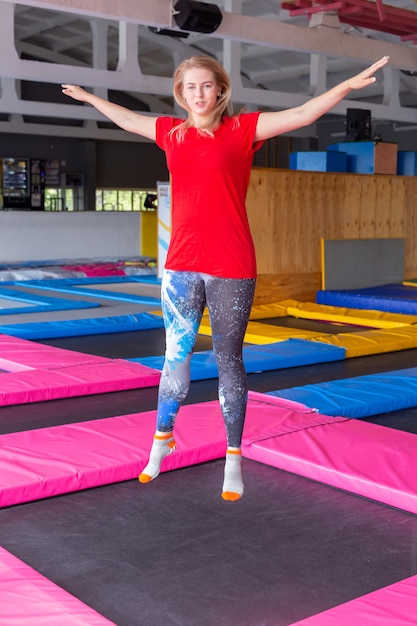 Jeune femme heureuse sautant sur un trampoline à l'intérieur.