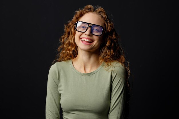 Une jeune femme heureuse et souriante portant des lunettes regarde la caméra avec un sourire joyeux.