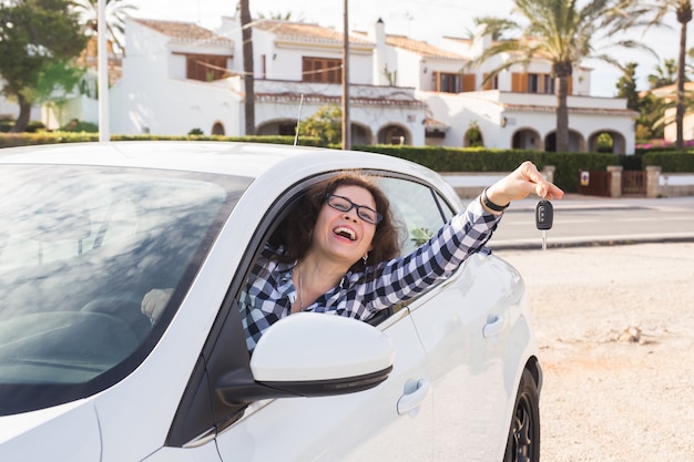 Jeune femme heureuse teste une nouvelle voiture et montre la clé