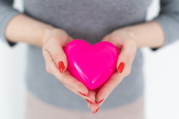 Une jeune femme heureuse tient le coeur rouge du symbole de l'amour. Isolé sur fond de studio modèle féminin.