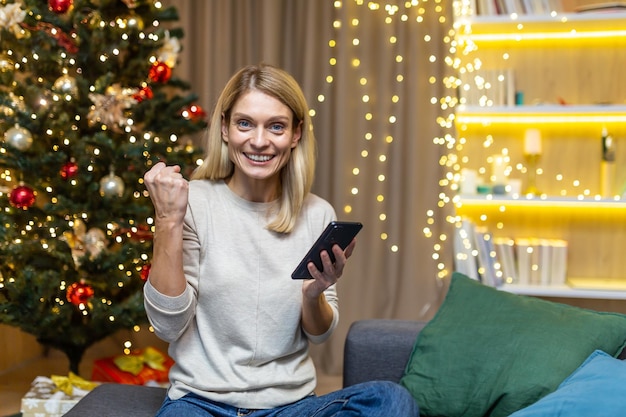 Une jeune femme heureuse tient un téléphone dans ses mains célèbre une victoire a remporté un prix a reçu de bonnes nouvelles