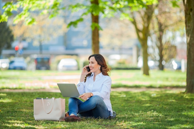 Jeune femme heureuse travaille sur un ordinateur portable dans la nature