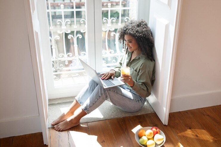 Photo une jeune femme heureuse utilisant un ordinateur portable en profitant d'un jus à la maison