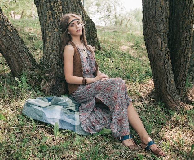 Jeune femme hippie assise près d'un arbre dans la forêt