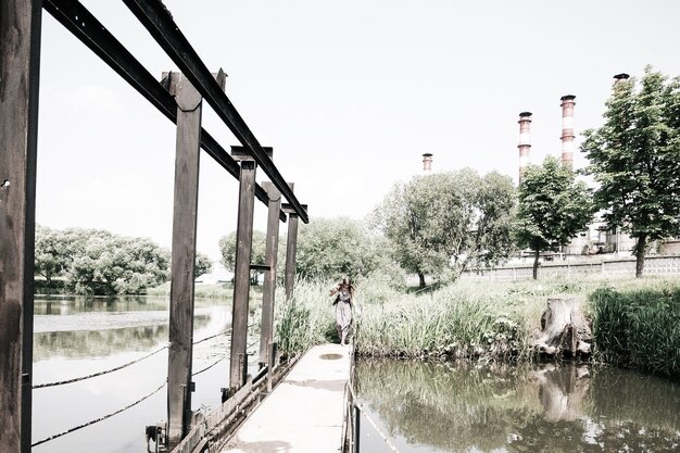 Jeune femme hippie debout sur un pont en bois le jour d'été