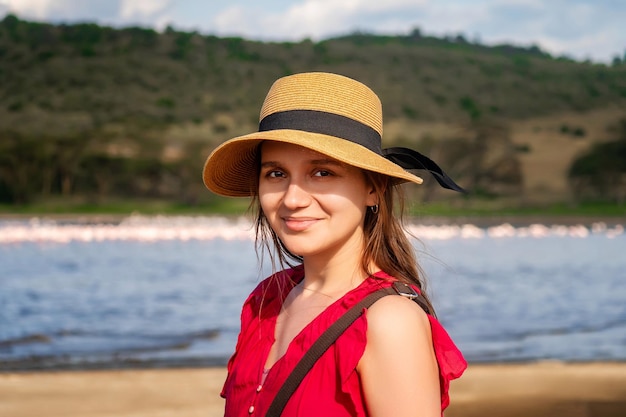 Une jeune femme hipster élégante avec un chapeau qui marche sur la toile de fond des éléphants dans la savane une jeune femme heureuse en T-shirt rouge explorant les montagnes ensoleillées concept de voyage et de voyage