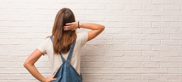 Jeune femme hipster par derrière pensant à quelque chose