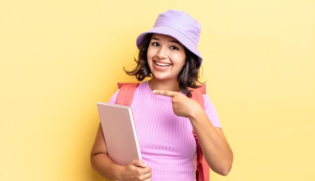 Jeune femme hispanique à l'air excité et surpris en pointant sur le côté. concept de retour à l'école