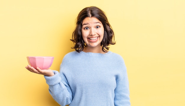 jeune femme hispanique à l'air heureuse et agréablement surprise. concept de bol vide