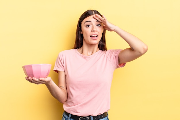 Jeune femme hispanique à l'air heureuse, étonnée et surprise. concept de bol vide