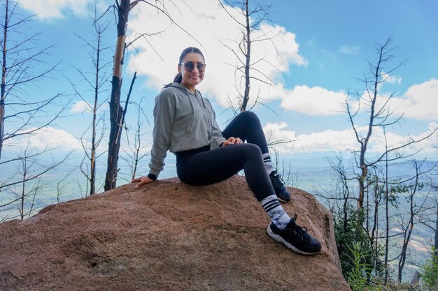 Une jeune femme hispanique assise sur un rocher et profitant de la belle nature