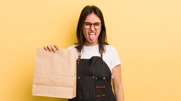 Jeune femme hispanique avec une attitude joyeuse et rebelle plaisantant et tirant la langue sur le concept de livraison de restauration rapide