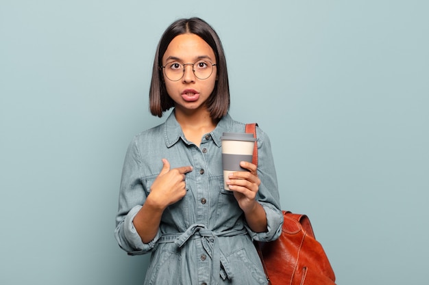 Jeune femme hispanique à choqué et surpris avec la bouche grande ouverte, pointant vers soi