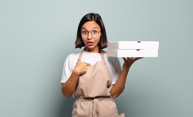 Jeune femme hispanique à choqué et surpris avec la bouche grande ouverte, pointant vers soi