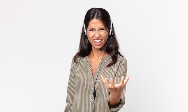 Jeune femme hispanique à la colère, agacée et frustrée par un casque. concept de télémarketing