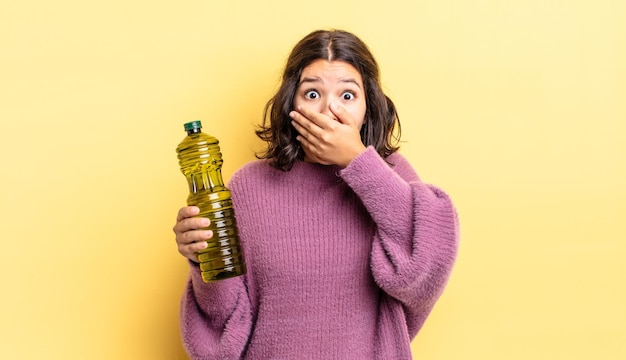 Jeune femme hispanique couvrant la bouche avec les mains avec un choc. notion d'huile d'olive