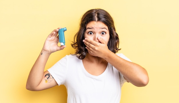 Jeune femme hispanique couvrant la bouche avec les mains avec un concept d'asthme choqué