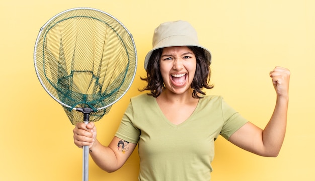 Jeune femme hispanique criant agressivement avec une expression de colère. concept de filet de pêcheur