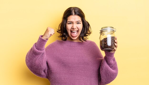 Jeune femme hispanique criant agressivement avec une expression de colère. concept de grains de café