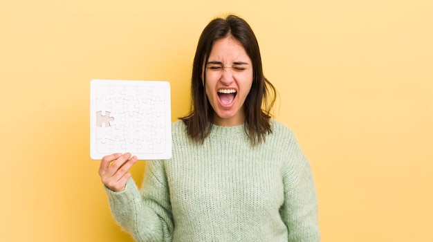 Jeune femme hispanique criant agressivement à la recherche d'un concept de puzzle très en colère