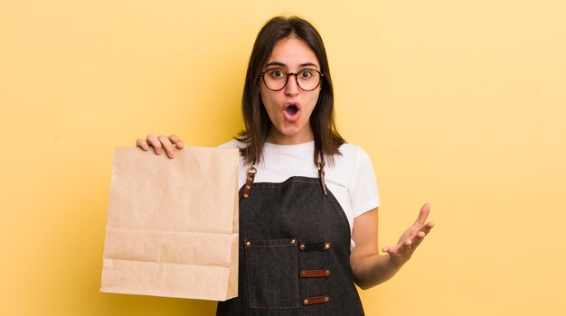 Jeune femme hispanique étonnée choquée et étonnée par un incroyable concept de livraison de restauration rapide surprise