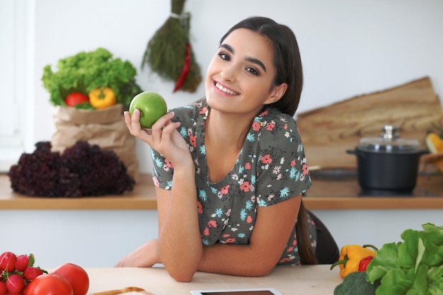 Jeune femme hispanique ou étudiante cuisiner dans la cuisine Fille utilisant une tablette pour faire des achats en ligne ou trouver une nouvelle recette