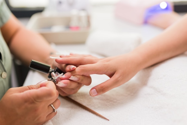 Jeune femme hispanique faisant la manucure avec un détail d'ongle en fibre de verre professionnel brésilien