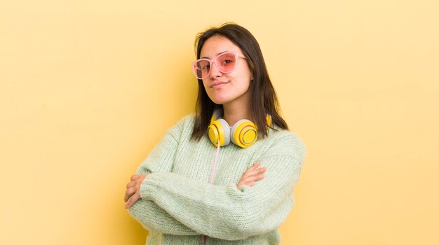 Jeune femme hispanique haussant les épaules, se sentant confus et incertain concept d'écouteurs et de lunettes de soleil