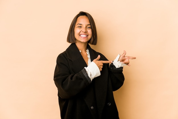 Jeune femme hispanique isolée excitée pointant avec l'index loin.