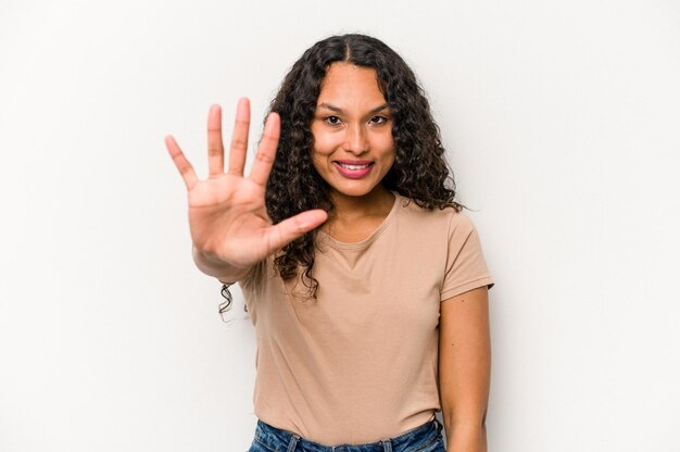 Jeune femme hispanique isolée sur fond blanc souriant joyeux montrant le numéro cinq avec les doigts