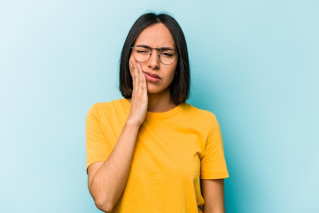 Jeune femme hispanique isolée sur fond bleu ayant une forte douleur aux dents douleur molaire