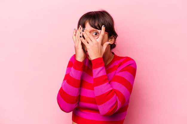 Jeune femme hispanique isolée sur fond rose cligner des yeux effrayée et nerveuse