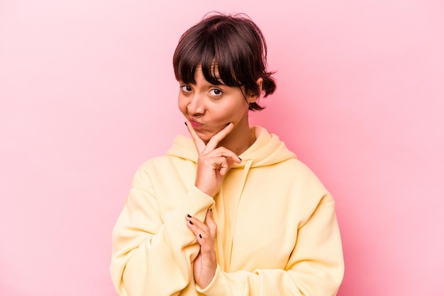 Jeune femme hispanique isolée sur fond rose envisageant de planifier une stratégie en pensant à la voie d'une entreprise