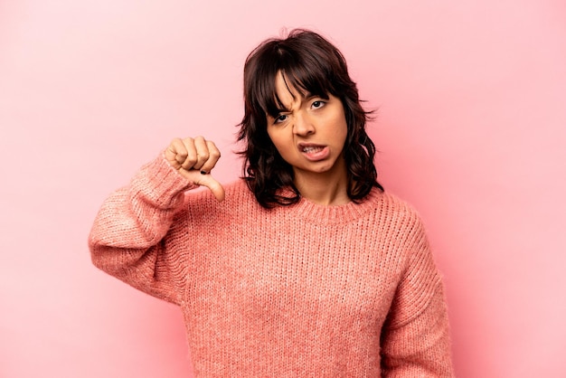 Jeune femme hispanique isolée sur fond rose montrant le pouce vers le bas et exprimant son aversion