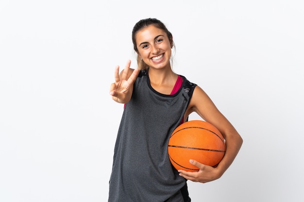 Jeune femme hispanique jouant au basket-ball sur fond blanc isolé heureux et comptant trois avec les doigts