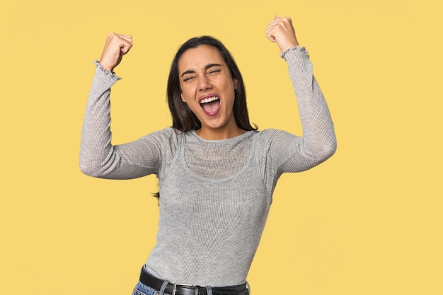 Une jeune femme hispanique lève le poing après un concept gagnant.